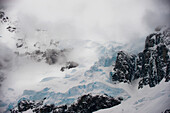 Storm clouds over the rocky, ice packed glacier at Lemaire Channel along the Antarctic Peninsula; Antarctic Peninsula, Antarctica