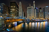 View of the Chicago River crossing the DuSable Bridge and cityscape of iconic office towers, with 333 North Michigan, the London Guarantee Building, Mather Tower, 35 East Whacker Building and the Kemper Building in the City of Chicago at night; Chicago, Cook County, Illinois, United States of  America