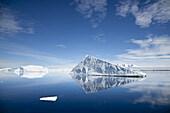 An iceberg reflected in still polar waters.