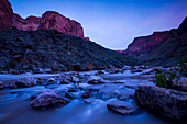Colorado river rushing over stones at twilight.