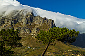 Clouds hover over a rocky mountainside.