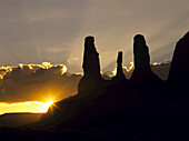 Three Sisters Butte rock formation silhouetted at sunset.