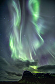 The northern lights dance over a mountain range on Iceland's South Coast; Vik, Southern Region, Iceland