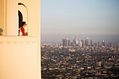A young woman looks out from Griffith Observatory at the Los Angeles skyline.