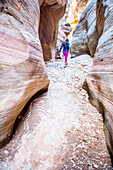 Eine junge Frau wandert ein Flussbett hinauf auf der Suche nach Slot Canyons im Zion National Park.