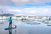 A man paddleboarding on the Jokulsarlon glacier lagoon.