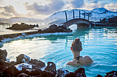 Eine Frau schwimmt in der blauen Lagune von Island.