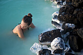 Eine Frau schwimmt in der blauen Lagune in Island.