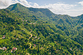 Überblick über den Berghang mit Häusern auf dem Berg Abang, mit blauem, bewölktem Himmel und üppiger Vegetation; Abang, Kabupaten Karangasem, Bangli Regency, Bali, Indonesien