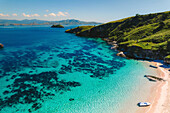 Aerial view a motor boats beached on the shore of a pink sand beach and people enjoying the seaside along the shore of Padar Island in Komodo National Park; East Nusa Tenggara, Lesser Sunda Islands, Indonesia