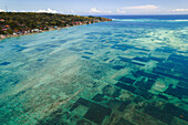 Luftaufnahme der Wasserstraße zwischen Nusa Lembongan und Nusa Ceningan, die kleine Boote zeigt, die über den Unterwasserflecken der Algenzucht im flachen, türkisfarbenen Wasser vertäut sind; Klungkung Regency, Ostbali, Bali, Indonesien