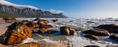 Rocky beach with Atlantic Ocean surf at Kogel Bay along the scenic R44 Route with the Kogelberg Mountains in the distance; Kogel Bay, Cape Town, Western Cape, South Africa