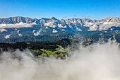 Vista through the mist overlooking the Wetterstein Mountains in the ski resort area of Garmish-Partenkirchen in summer; Garmish-Partenkirchen, Bayern, Germany