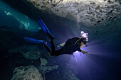 Scuba diver exploring an underwater cave with a light; Tulum, Quintana Roo, Mexico