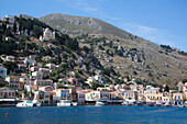 Berghang und malerische Uferpromenade des Hafens von Gialos, Insel Symi (Simi); Dodekanes-Inselgruppe, Griechenland