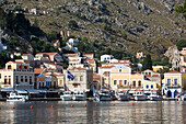 Boats moored along the shore at Gialos Harbor, Symi (Simi) Island; Dodecanese Island Group, Greece