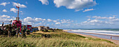Beachfront buildings and a person standing on the shore watching the ocean surf along Dolphin Beach at Jeffrey's Bay; Eastern Cape, South Africa