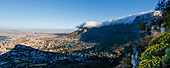 Wolkenformation, die den Tischtuch-Effekt über dem Tafelberg erzeugt, mit einem Überblick über die Skyline von Kapstadt vom Signal Hill und dem Schatten des Lion's Head; Kapstadt, Provinz Westkap, Südafrika