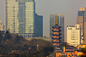 Eine Pagode aus der Ming-Dynastie am Jiming-Tempel, mit der modernen Stadt dahinter, Nanjing, Provinz Jiangsu, China; Jiming-Tempel, Nanjing, Provinz Jiangsu, China.