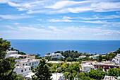 Weiß getünchte Gebäude in Capri-Stadt auf einem sattelförmigen Plateau hoch über dem Meer mit dem Hafen der Insel, Marina Grande, darunter; Neapel, Capri, Italien