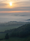 Nebelbank fließt bei Sonnenaufgang über den Long Man of Wilmington im South Downs National Park; Brighton, East Sussex, England