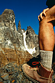 Das Bein eines Wanderers während einer Pause am Fuße eines Granitgipfels in den Anden; Chile.