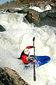 Wildwasserkajakfahrer bezwingt einen großen Wasserfall; Great Falls, Potomac River, Virginia/Maryland.