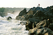 Kayaker carries boat up the rocks of Great Falls on the Potomac River.; POTOMAC RIVER.