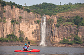 A kayaker paddles towards a large waterfall on the Congo river.; Congo River, Democratic Republic of the Congo.