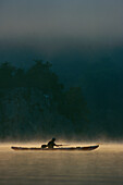 Ein Kajakfahrer paddelt in der Morgendämmerung durch den Nebel auf dem Potomac River; Potomac River, Maryland.