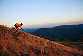 A cyclist rides downhill through a meadow.; Pocahantas County, West Virginia.