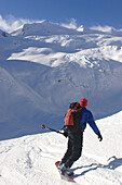 Ein Backcountry-Snowboarder fährt ein Schneefeld in Richtung eines Gletschers hinunter; Selkirk Mountains, British Columbia, Kanada.