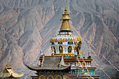 Das Dach eines buddhistischen Tempels im Labrang-Kloster mit den Bergkämmen des Himalaya im Hintergrund; Labrang, Amdo, Tibet