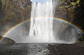 Kaskadenförmiger Wasserfall und Regenbogen; Island