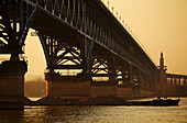 Silhouette of ship passing under the Yangtze Bridge, crossing the River Yangtze at twilight; Nanjing, Jiangsu Province, China