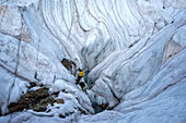 Ein Höhlenforscher seilt sich ab und beginnt seinen Abstieg in eine grosse Gletschermühle.