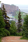 View of the town of Perce, and Perce Rock from a nearby hill.; Perce, Gaspe Peninsula, Quebec, Canada.