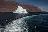 Boat wake next to a small iceberg floating in Greenland's Kaiser Franz Joseph Fjord; East Greenland, Greenland
