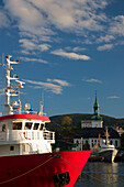 Angedockte Boote im Hafen von Bergen, mit einem Kirchengebäude am Ufer; Bergen, Norwegen