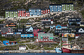 Nahaufnahme der farbenfrohen Gebäude an den felsigen Klippen entlang der Küste in der Hafenstadt Qaqortoq an der Südspitze Grönlands; Qaqortoq, Südgrönland, Grönland