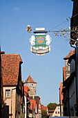 A Sign Hanging From A Building Against A Blue Sky; Rothenburg Ob Der Tauber Bavaria Germany