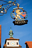 Hängeschild für ein Hotel und ein Uhrenturm an einem Gebäude; Rothenburg Ob Der Tauber Bayern Deutschland