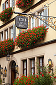 Schild für ein Hotel hängt an der Seite des Gebäudes mit blühenden roten Blumen in Blumenkästen; Rothenburg Ob Der Tauber Bayern Deutschland