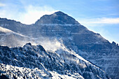 Berggipfel mit wehendem Schnee über Bergkämmen und blauem Himmel; Waterton Alberta Kanada