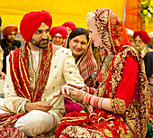 Braut und Bräutigam tauschen bei einer indischen Hochzeitszeremonie die Ringe aus; Ludhiana, Punjab, Indien
