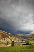 A Stone Shed In A Field With Storm Clouds Overhead; Swaledale England