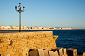 A Lamp Post And Wooden Crates Along The Water's Edge; Cadiz, Andalusia, Spain