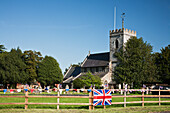 Englische Dorfkirche und Fahne an einem Zaun; Claverdon Warwickshire England