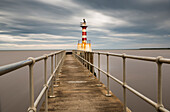 Ein rot und weiß gestreifter Leuchtturm am Ende eines Piers; Amble Northumberland England