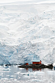 Small Buildings Reflected In The Water On The Frozen Coastline; Antarctica